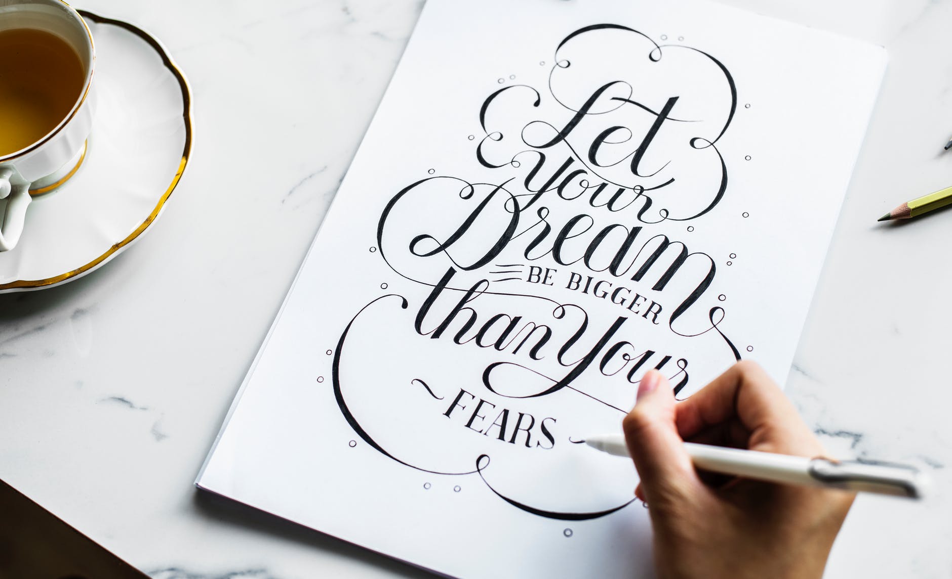 person writing calligraphy style quote on table