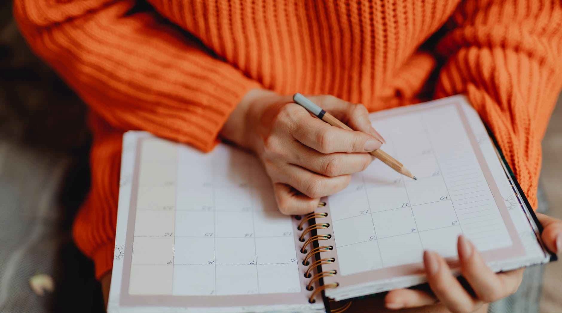 person holding pen and planner