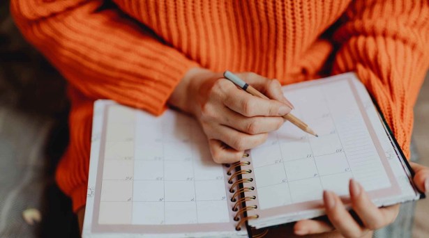 person holding pen and planner